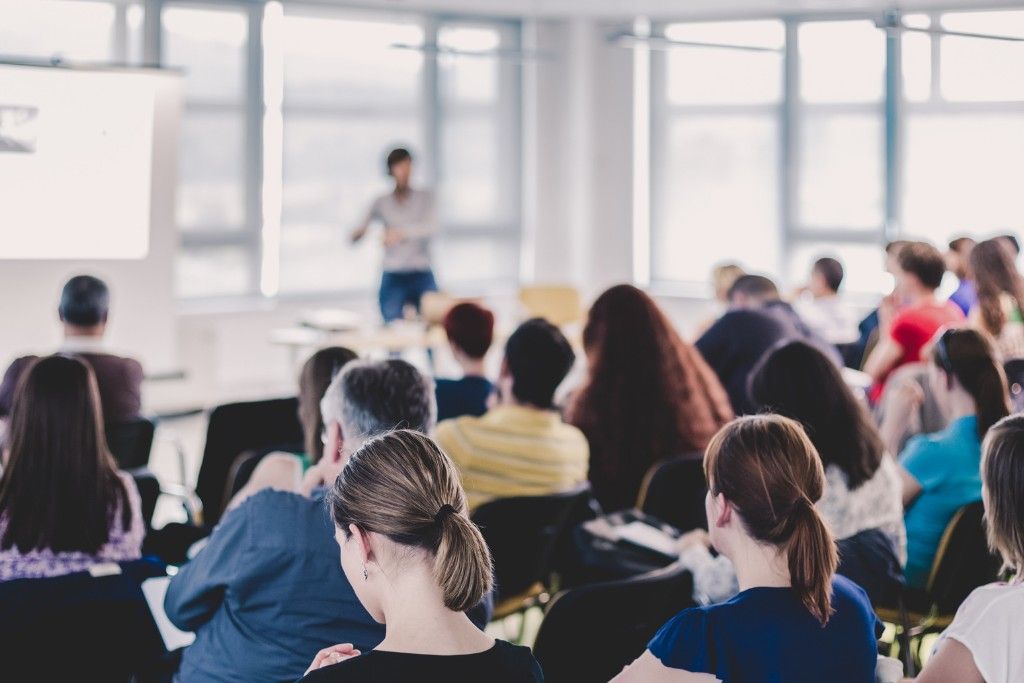 Professional speaker engaging with a diverse conference audience during a keynote presentation